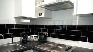 Une cuisine avec des carreaux noirs et blancs, une cuisinière, une bouilloire et une machine à café.
