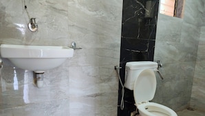 Une salle de bain avec un lavabo blanc, des toilettes et un mur en marbre.