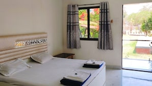 Une chambre d’hôtel avec un lit, une table de chevet, une fenêtre avec des rideaux et une vue sur l’extérieur.