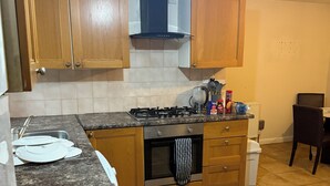 Een keuken met houten kastjes, een gasfornuis, een magnetron en een kleine oven.