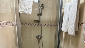 Een badkamer met douche, toilet en wastafel.