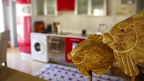 A kitchen with red cabinets, a washing machine, and a wooden decorative piece. - Stay U-nique Apartments Monec (Barcelona)