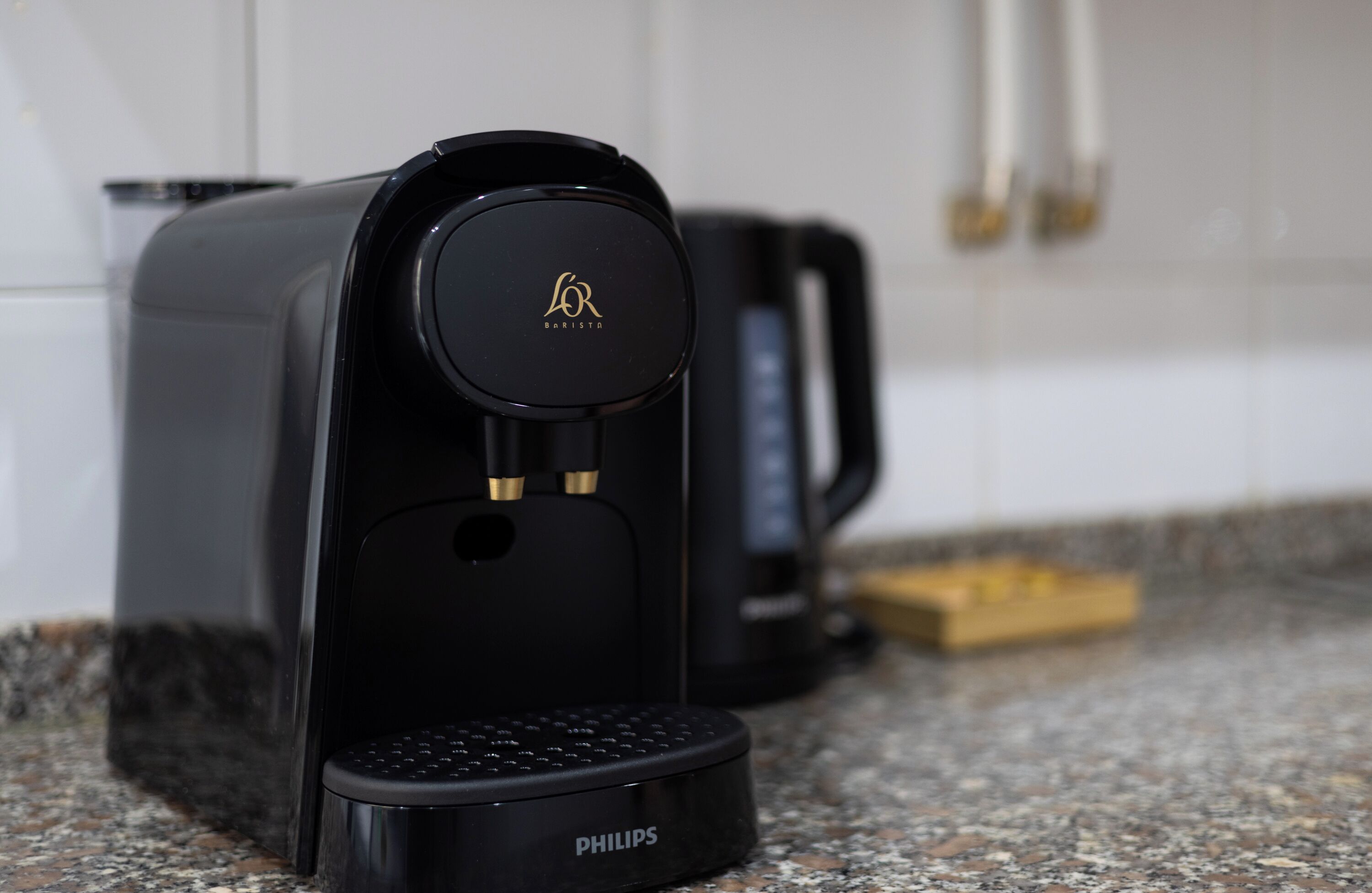 Une machine à café noire, ornée du logo de la marque et du mot « PHILIPS », est posée sur un plan de travail en granit.