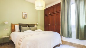 A bedroom with a large bed, wooden wardrobe, and a window with curtains.