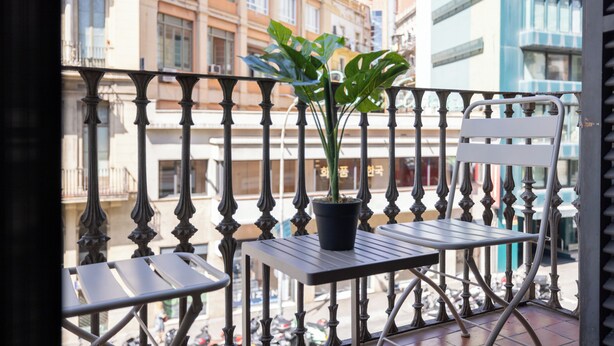 A balcony with a potted plant, a white chair, and a table.