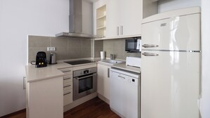 A modern kitchen with a built-in oven, dishwasher, microwave, and a stainless steel range hood.