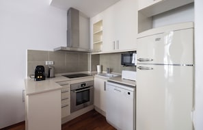 Een moderne keuken met een ingebouwde oven, vaatwasser, magnetron en een roestvrijstalen afzuigkap.