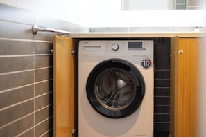 Een voorlader wasmachine met bedieningspaneel, een badge voor 10 jaar garantie en een deur van hout.