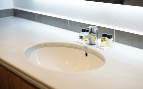 A bathroom sink with a faucet, a soap dispenser, and a bottle of hand soap.