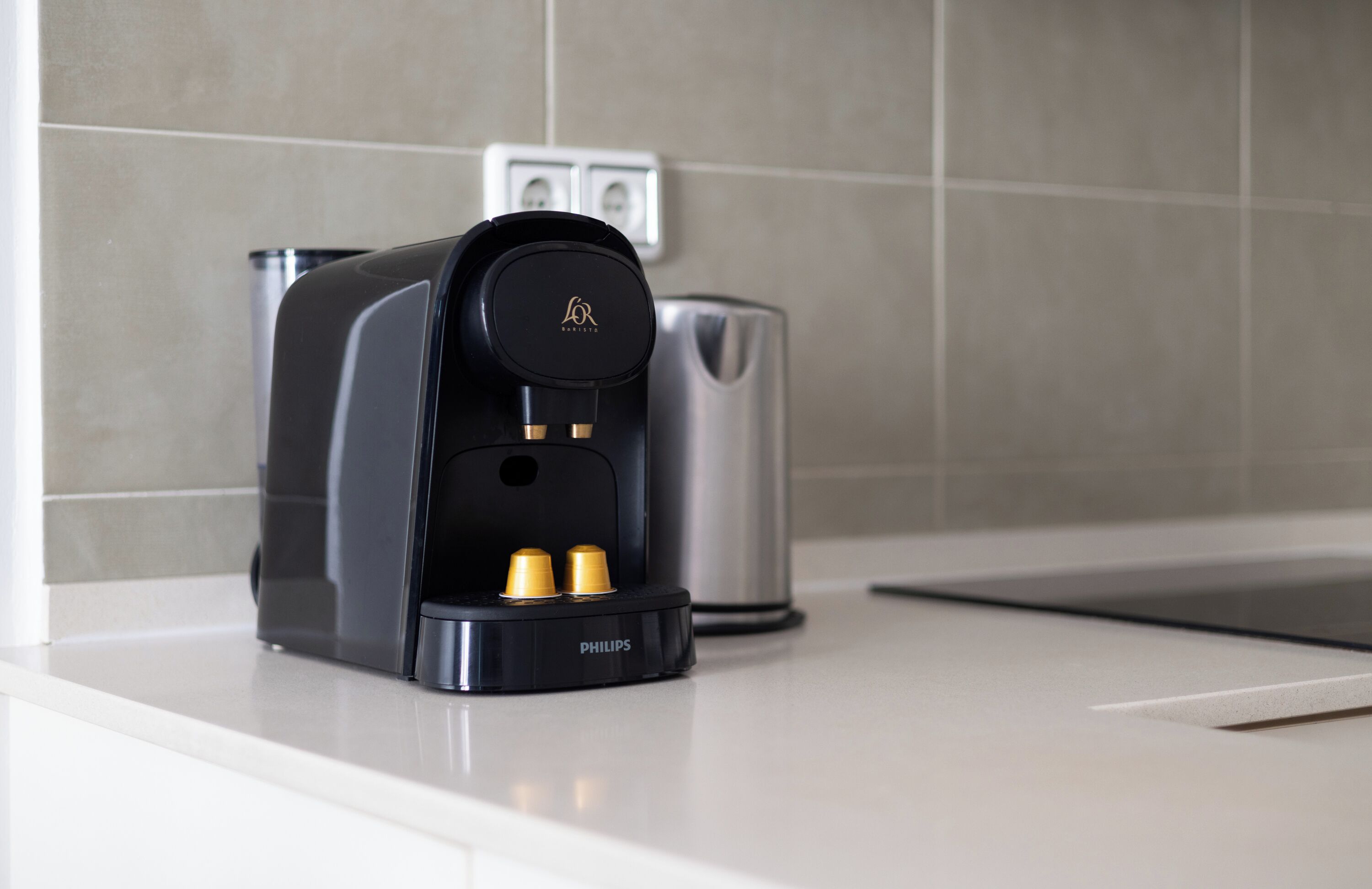 Une machine à café posée sur un plan de travail de cuisine, avec un appareil en acier inoxydable en arrière-plan.