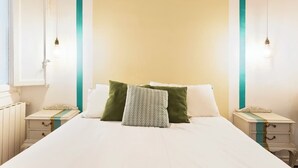 A neatly made bed with pillows, a bedside table, and a nightstand.