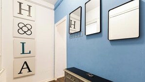 A hallway with a blue wall, a white door, and a black console table with a mirror and hooks.