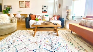 A living room with a sofa, a coffee table, and a patterned rug. - Stunning 2 Bed Apartment on the beach by Urban Roost (Worthing)
