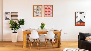 A dining area with a wooden table, white chairs, and a potted plant. - Stunning 2 Bed Apartment on the beach by Urban Roost (Worthing)