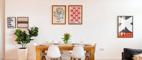 A dining area with a wooden table, white chairs, and a potted plant.