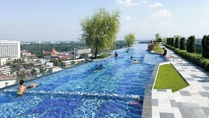 En swimmingpool med kristallklart blått vatten, omgiven av en gångbana med kakelplattor och en gräsyta.