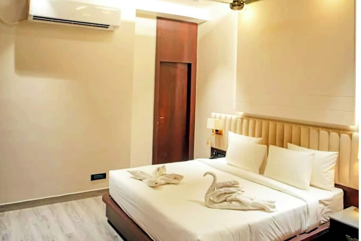 A modern bedroom with a bed, a ceiling fan, and an air conditioning unit.