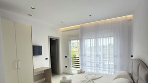 Een moderne slaapkamer met een groot bed, een kledingkast, een televisie en uitzicht op de omgeving.