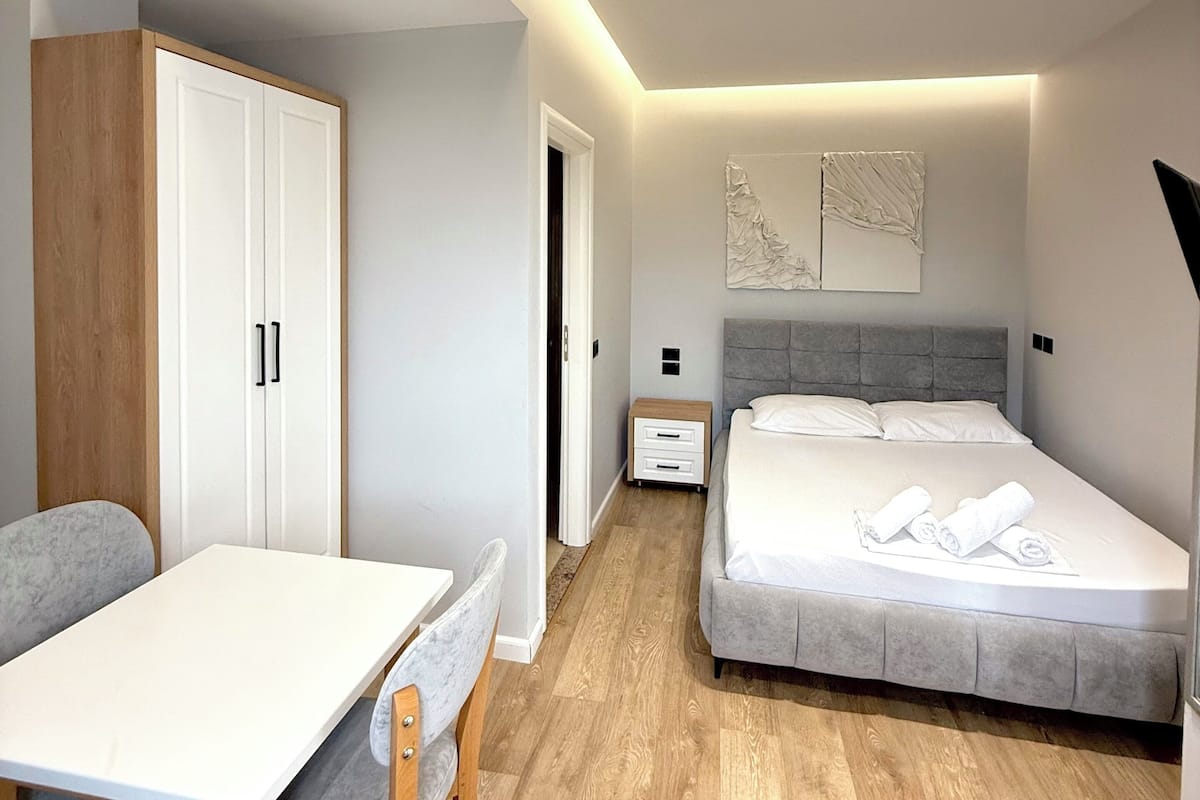A modern bedroom with a bed, bedside table, and a desk with a chair.