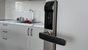 Een moderne keuken met witte kasten, een roestvrijstalen koelkast en een digitaal slot op de deur.