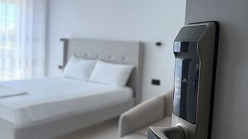 A modern hotel room with a bed, a chair, and a wall-mounted control panel.