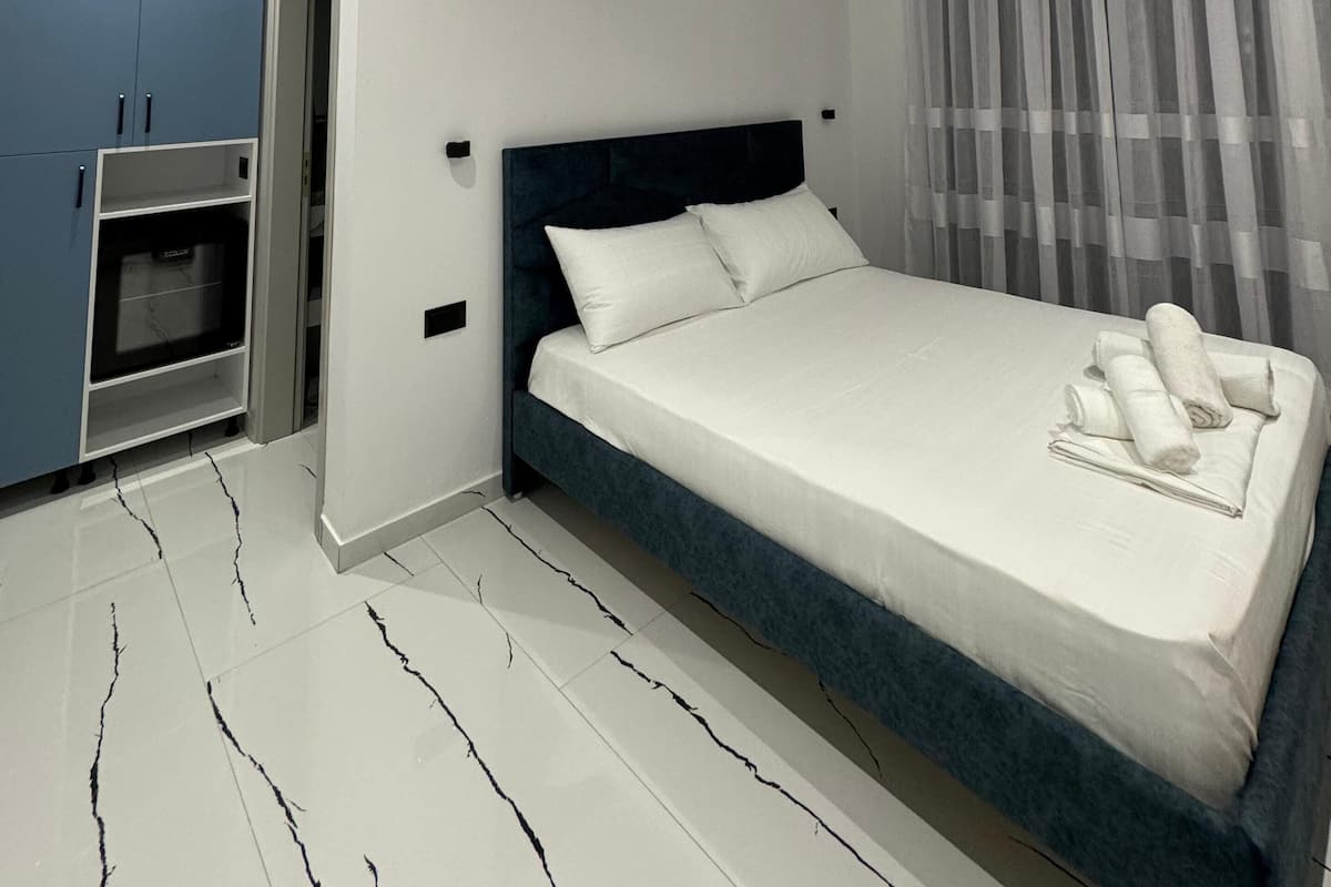 A modern bedroom with a large bed, a built-in wardrobe, and a small seating area.