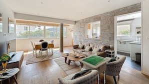 A spacious living area with a dining table, sofas, and a kitchen in the background.