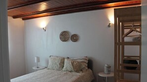Een slaapkamer met een bed, nachtkastje, lamp, decoratie aan de muur en een houten garderobe.