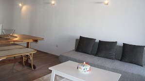Een woonkamer met een houten eettafel, een grijze bank en een witte salontafel.