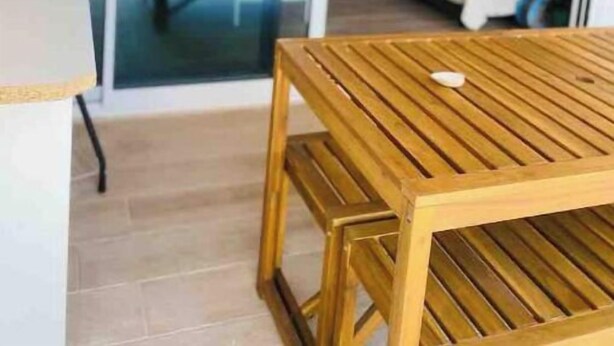 Een houten tafel en een bank in een kamer met uitzicht door een glazen deur.
