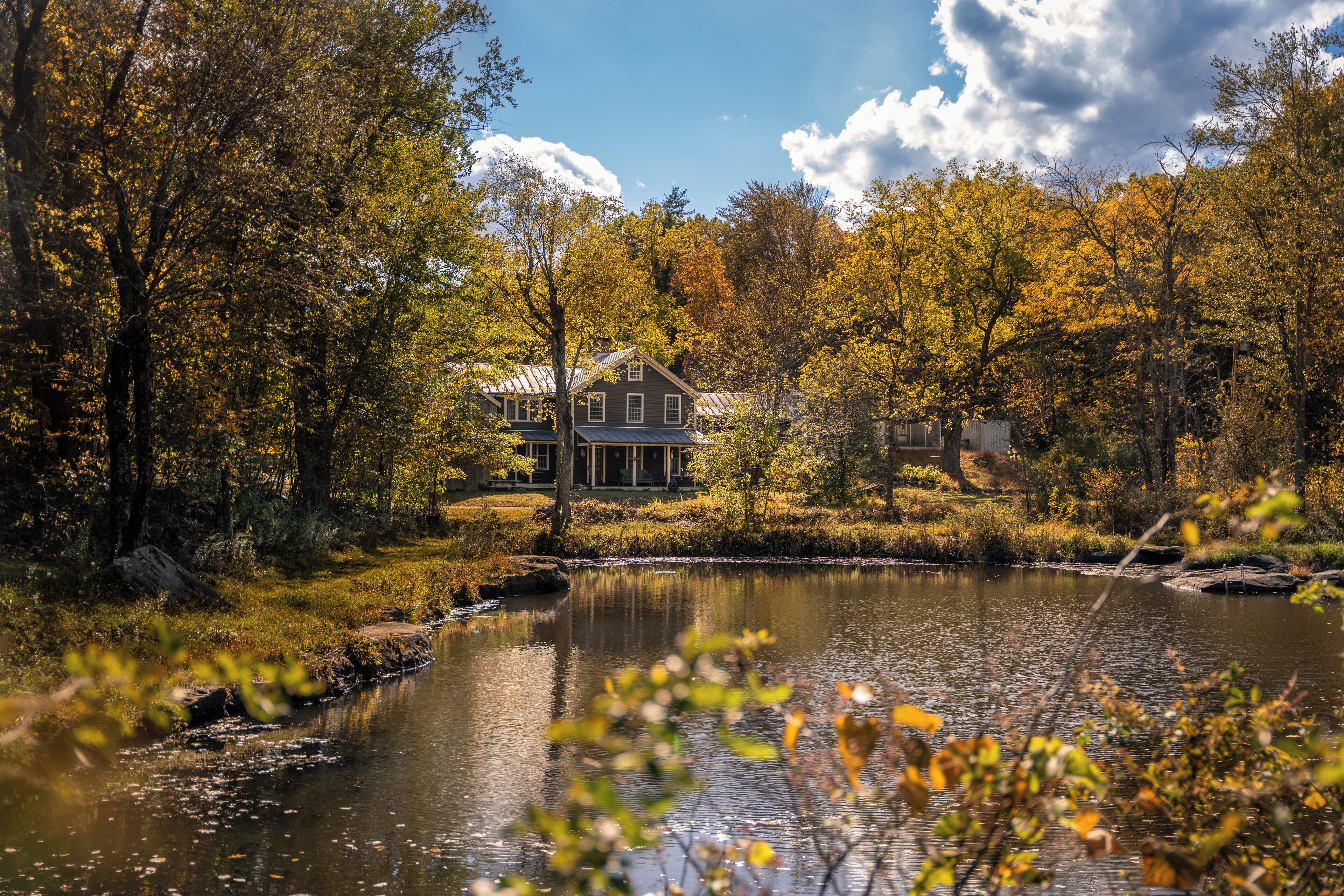 Una casa al costat d'un llac envoltada d'arbres d'octubre.