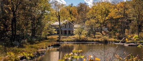 A house by a lake surrounded by autumn trees.