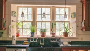 Een keuken met een groot raam, een spoelbak en drie hanglampen.
