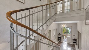 A grand staircase with a wooden handrail and metal balusters, leading to an upper floor.