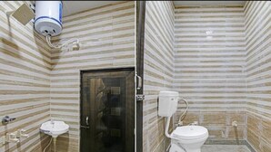 A bathroom with striped tile walls, a sink, toilet, and a shower area. - Hotel Mid Town (New Delhi)