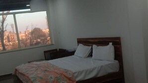 A bedroom with a bed, a window, and a view of buildings. - Hotel Mid Town (New Delhi)