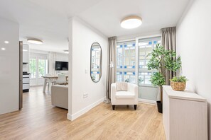 A modern living room with a sofa, a chair, a large mirror, and a potted plant.