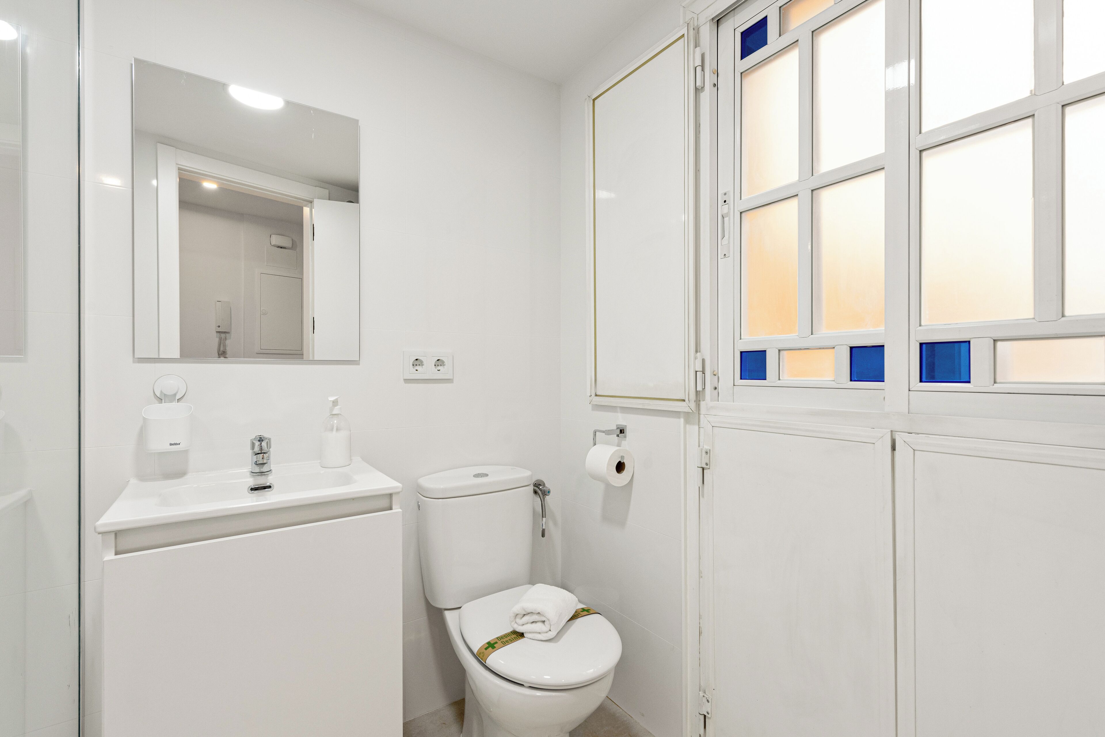 A white bathroom with a toilet, sink, and mirror.