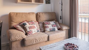 Ein Wohnzimmer mit einem beigen Sofa, einem Holztisch und einem Gemälde der Golden Gate Bridge.