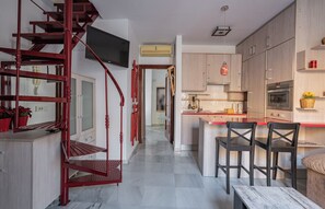 Une cuisine moderne avec des meubles en bois, un four encastré et un escalier rouge.