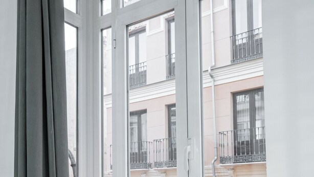 Une pièce dotée d’une grande fenêtre donnant sur un immeuble avec des balcons.