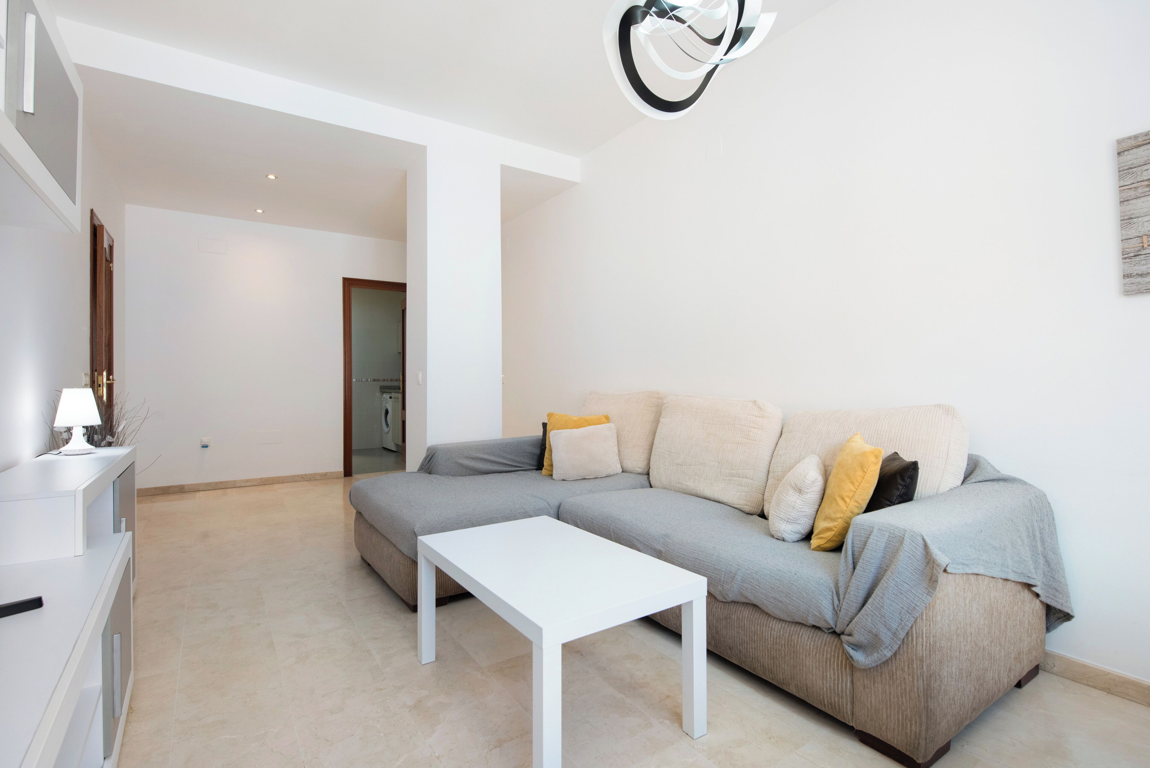 Una sala de estar moderna con un sofá gris, una mesa de centro blanca y un diseño minimalista.