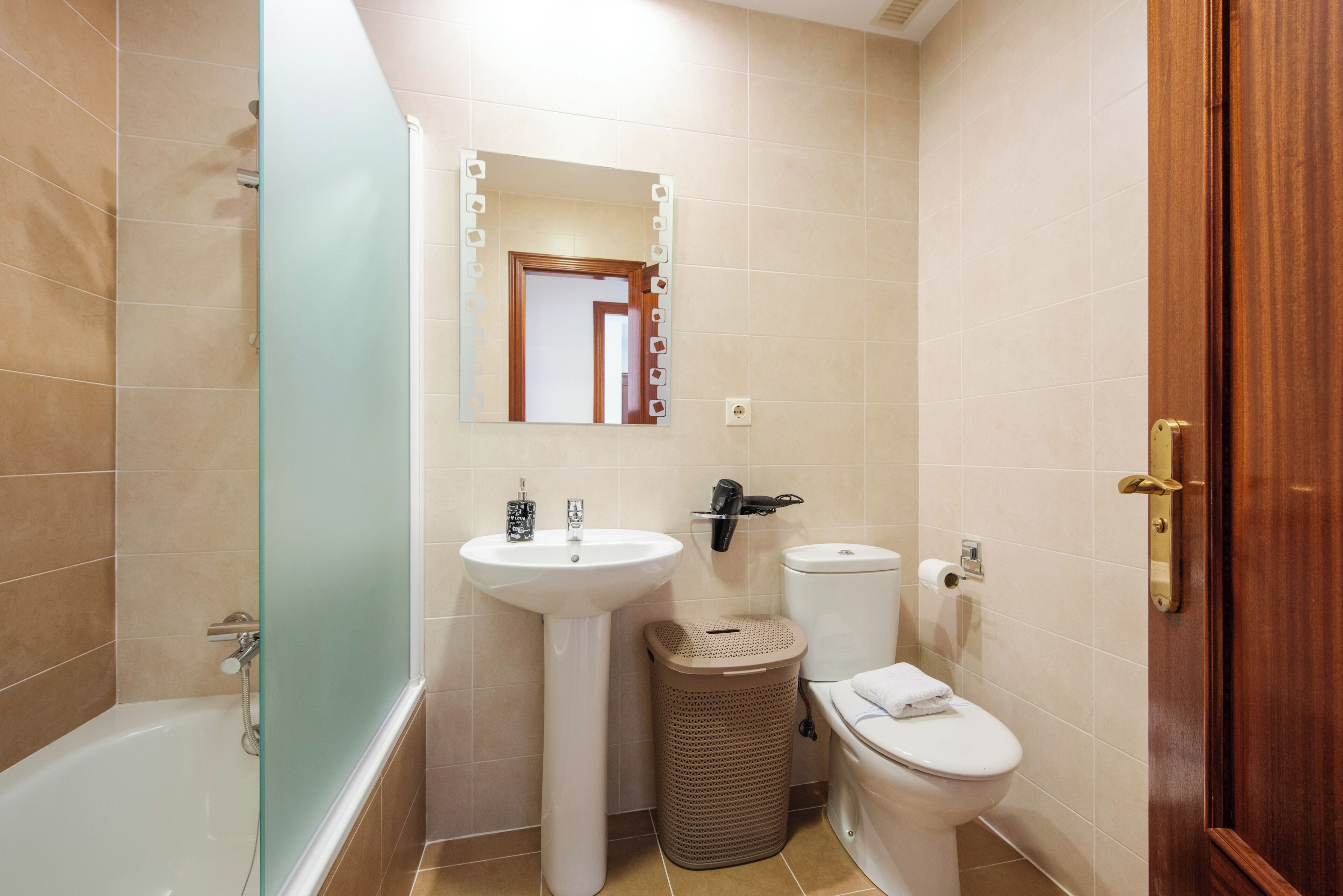Une salle de bain équipée d’une baignoire, d’un lavabo, de toilettes et d’une poubelle.