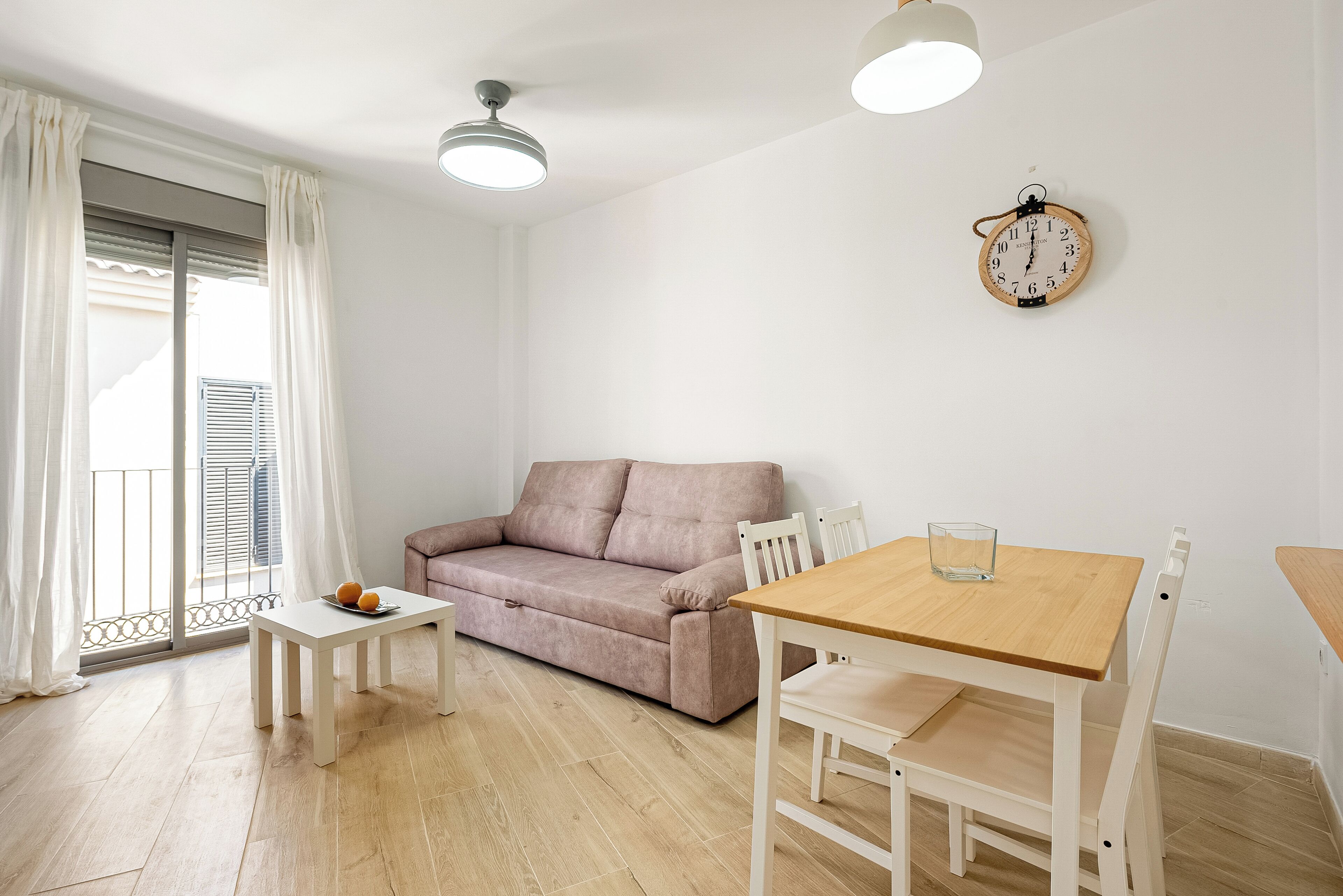 A living room with a sofa, a small table, and a wooden dining table with chairs.