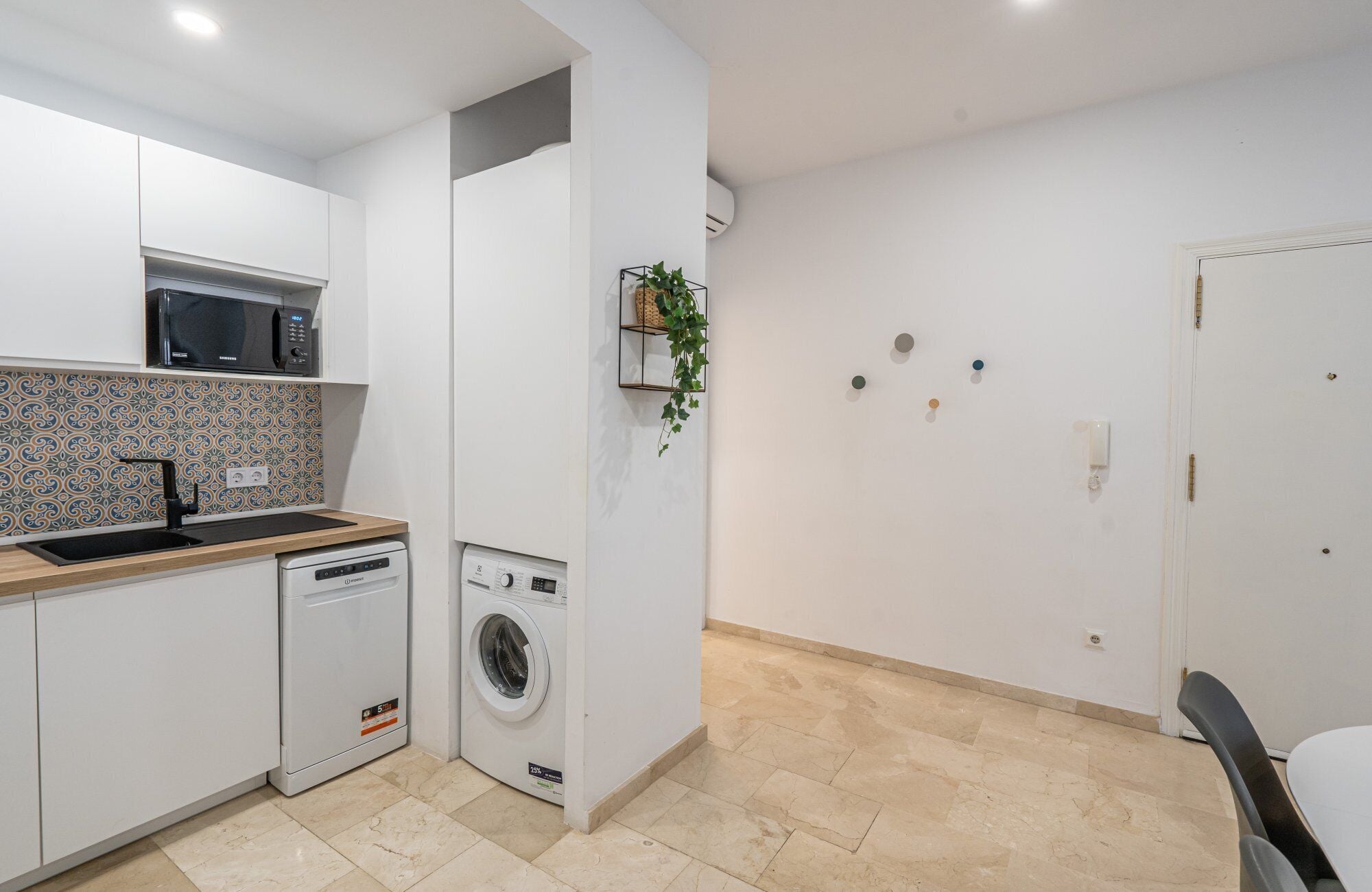 Una cocina compacta con microondas, lavabo y lavadora.