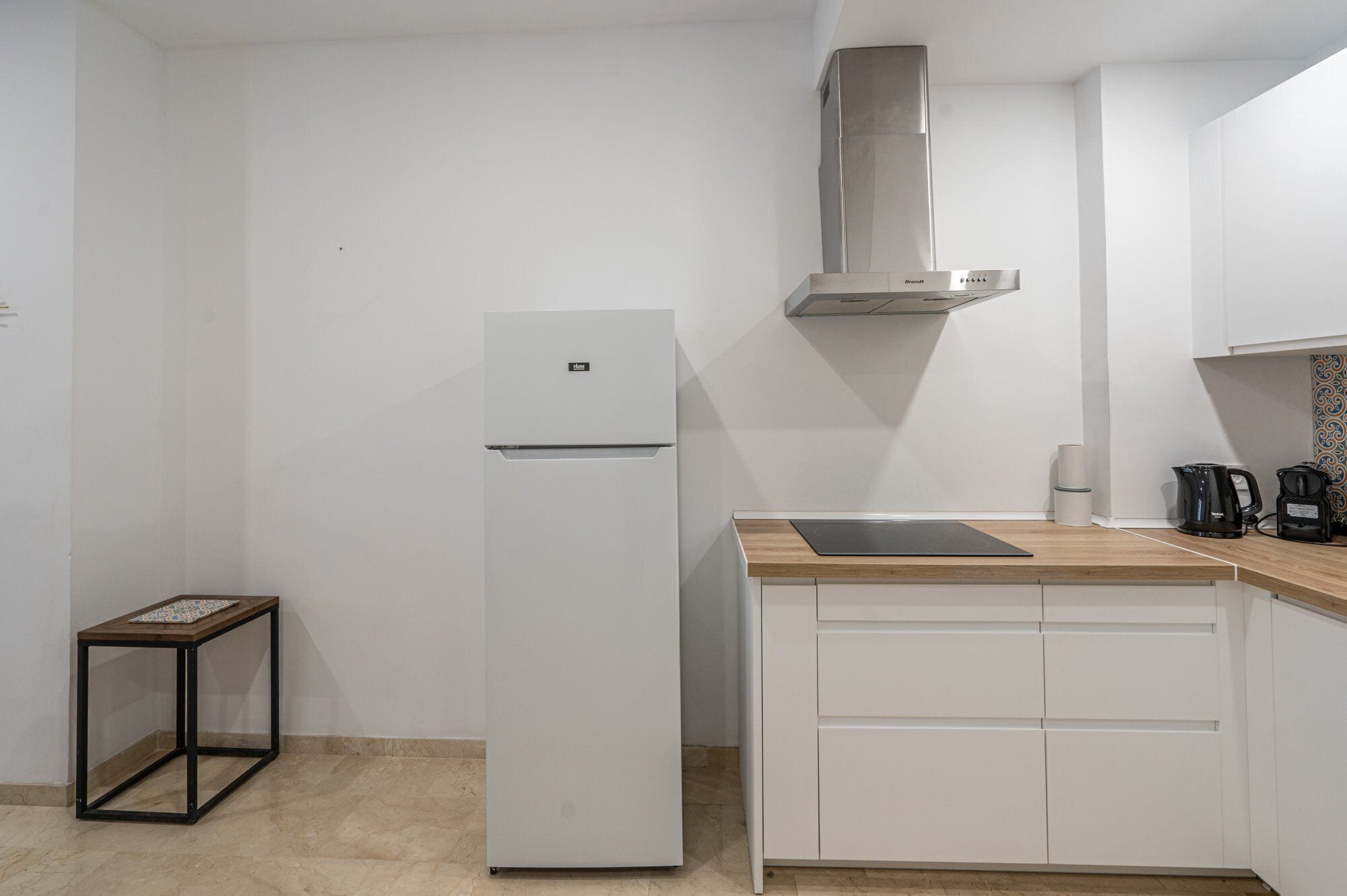 A kitchen with a white refrigerator, a wooden countertop, and a stainless steel range hood.