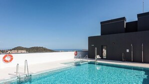 Una piscina en la azotea con agua azul cristalina, un flotador salvavidas y vistas a una colina distante.