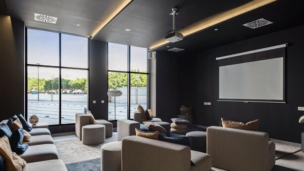 Un cine en casa moderno con pantalla grande, asientos cómodos y vistas al exterior.