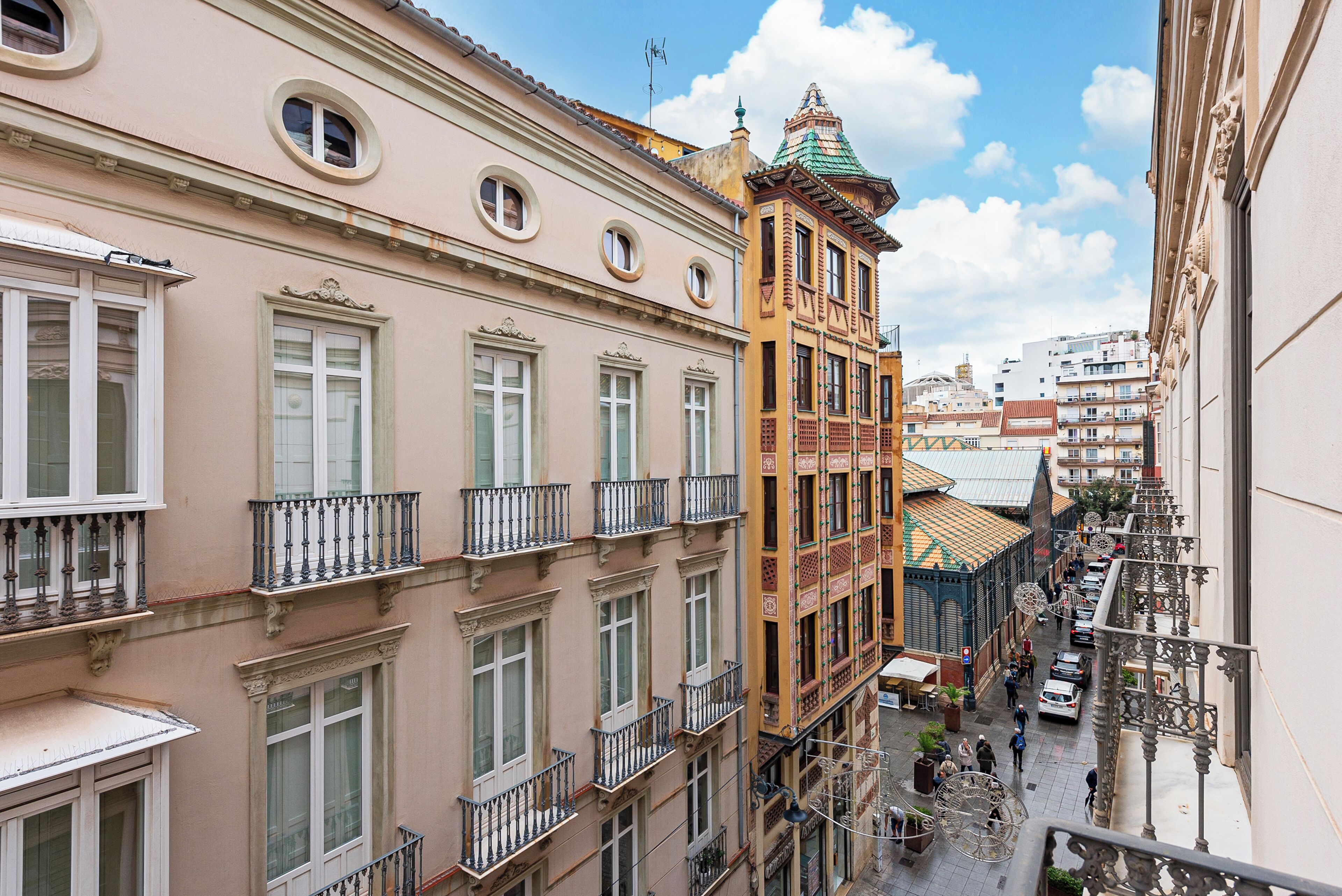 A narrow street with buildings on either side, featuring balconies and traditional architecture.