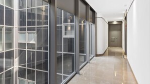 A hallway with large windows, a polished floor, and a door at the end. - Stay U-nique Apartment Sebastián Souvirón (Málaga)